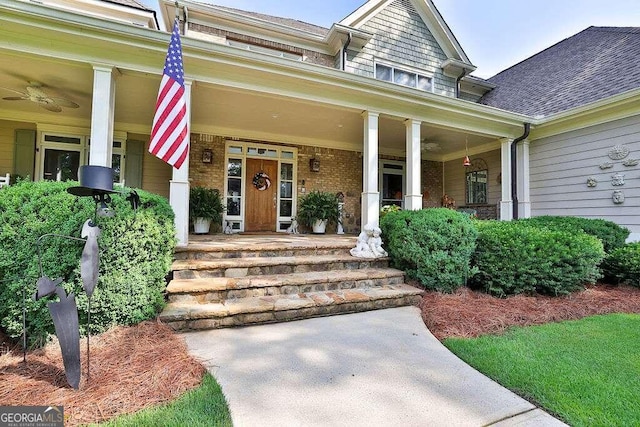doorway to property featuring covered porch, a shingled roof, and brick siding
