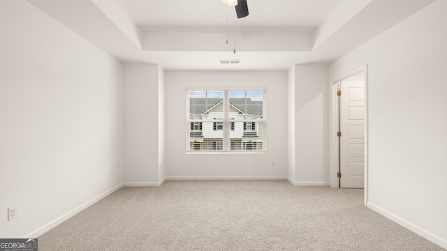 carpeted empty room featuring a tray ceiling and ceiling fan