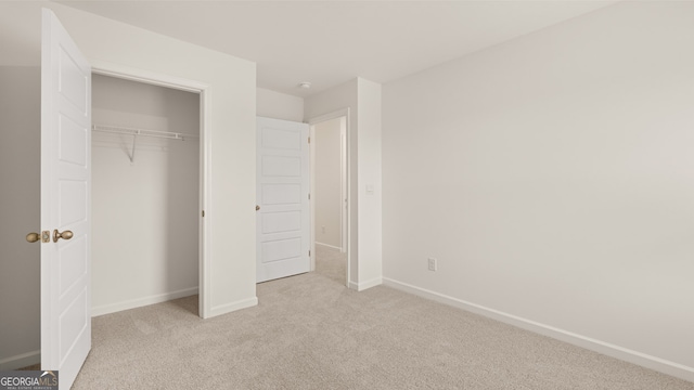 unfurnished bedroom featuring light carpet and a closet