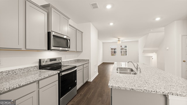 kitchen featuring stainless steel appliances, dark hardwood / wood-style flooring, sink, ceiling fan, and a kitchen island with sink