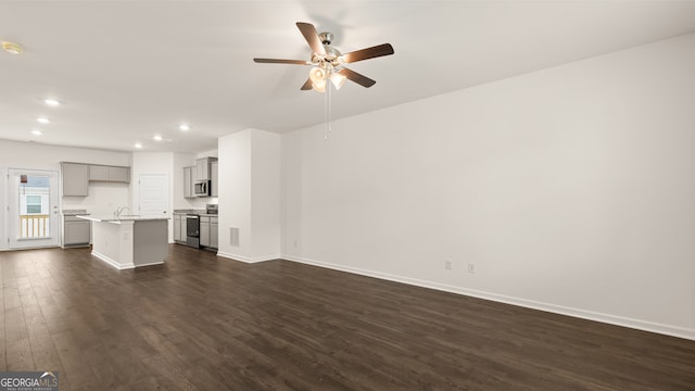 unfurnished living room featuring dark hardwood / wood-style flooring, sink, and ceiling fan