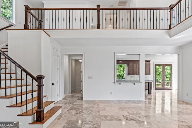 entryway featuring french doors, crown molding, and a high ceiling