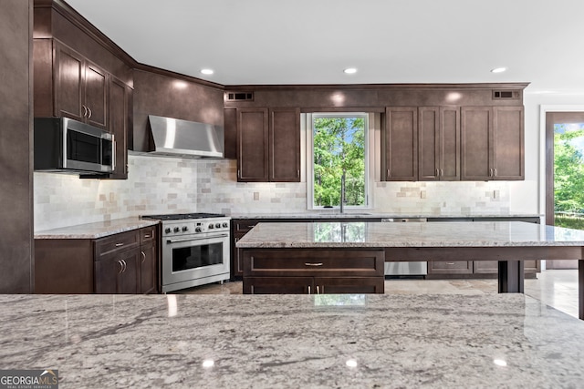 kitchen featuring stainless steel appliances, light stone countertops, and a wealth of natural light