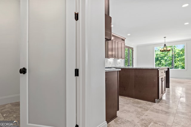 kitchen with tasteful backsplash, a kitchen island, dark brown cabinets, decorative light fixtures, and a notable chandelier