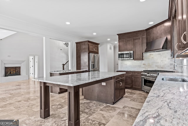 kitchen with light stone counters, high end appliances, tasteful backsplash, dark brown cabinets, and wall chimney exhaust hood