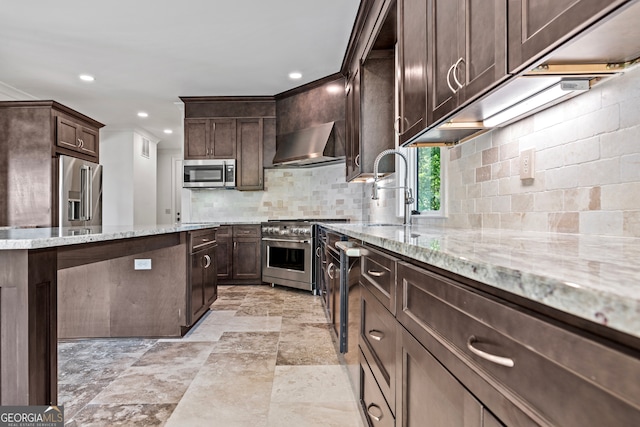 kitchen featuring wall chimney exhaust hood, premium appliances, light stone counters, and dark brown cabinets