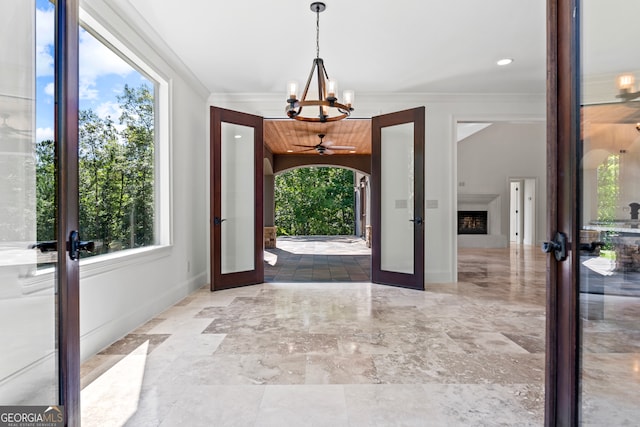 foyer featuring lofted ceiling, french doors, crown molding, and an inviting chandelier