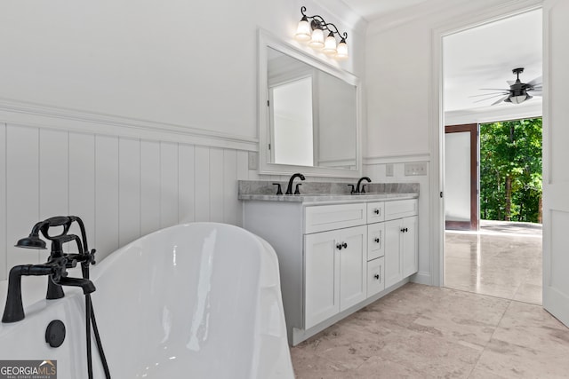 bathroom featuring ceiling fan, vanity, ornamental molding, and a washtub