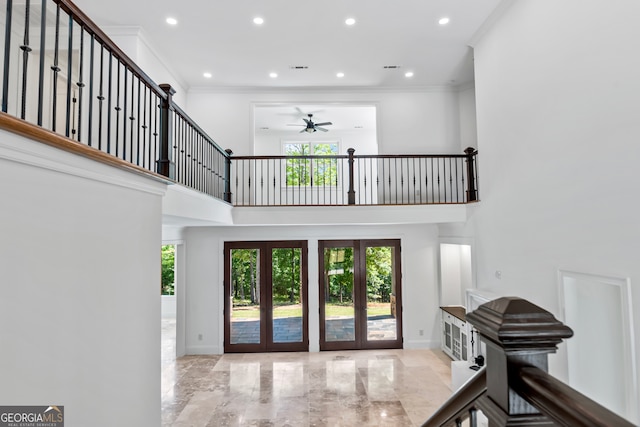 entrance foyer with a towering ceiling, french doors, ornamental molding, and ceiling fan