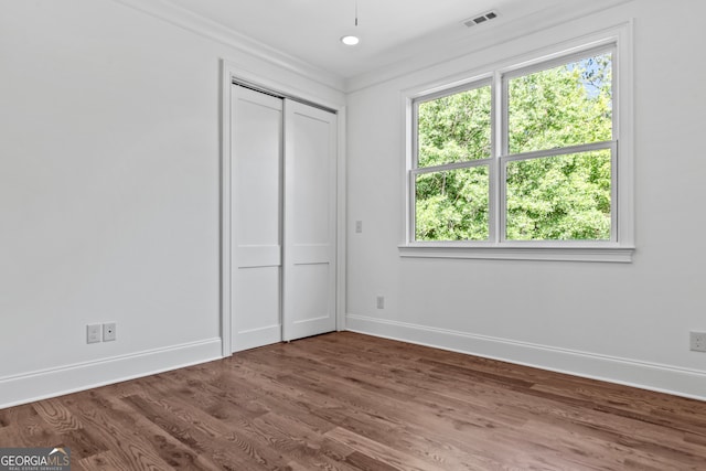 unfurnished bedroom featuring ornamental molding, hardwood / wood-style flooring, and a closet