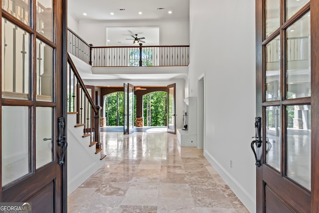 entrance foyer featuring ornamental molding, ceiling fan, a high ceiling, and french doors