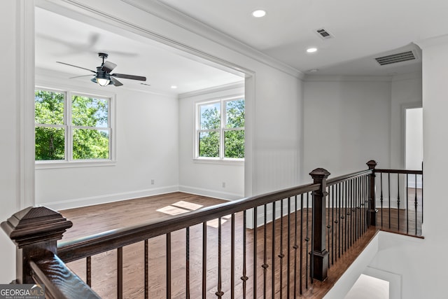 hall with crown molding, hardwood / wood-style floors, and a healthy amount of sunlight