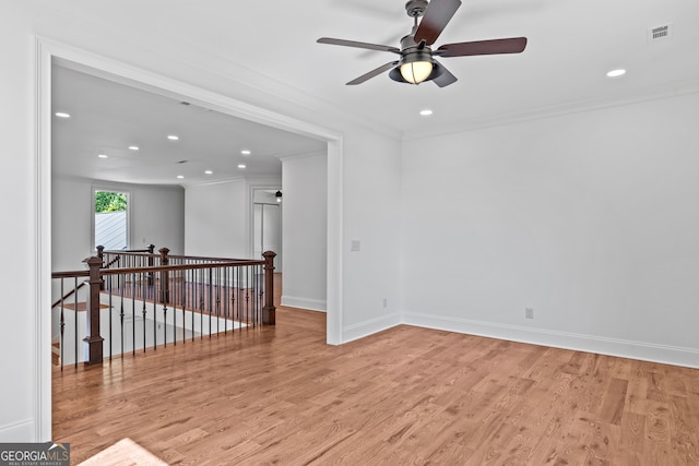 empty room featuring ceiling fan, light wood-type flooring, and crown molding