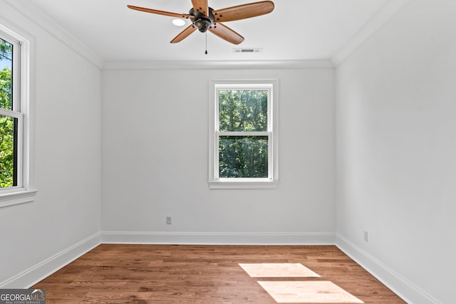 empty room with ceiling fan, crown molding, hardwood / wood-style flooring, and a healthy amount of sunlight