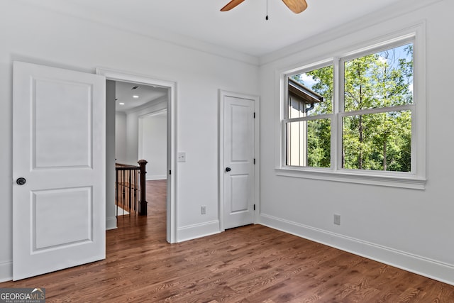 unfurnished bedroom featuring ceiling fan, dark hardwood / wood-style floors, and crown molding