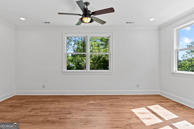 empty room featuring plenty of natural light, ornamental molding, light wood-type flooring, and ceiling fan