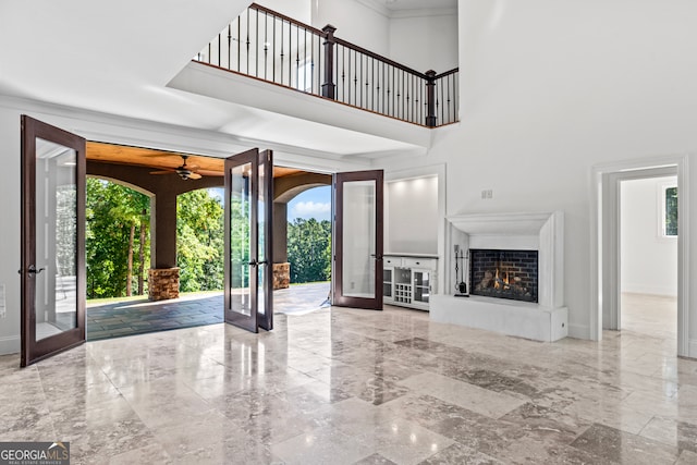 unfurnished living room featuring plenty of natural light, french doors, a high ceiling, and ceiling fan