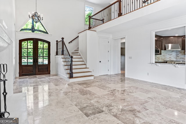 foyer with french doors, an inviting chandelier, plenty of natural light, and a high ceiling