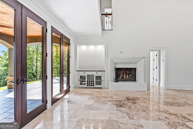 unfurnished living room featuring french doors, crown molding, and a wealth of natural light