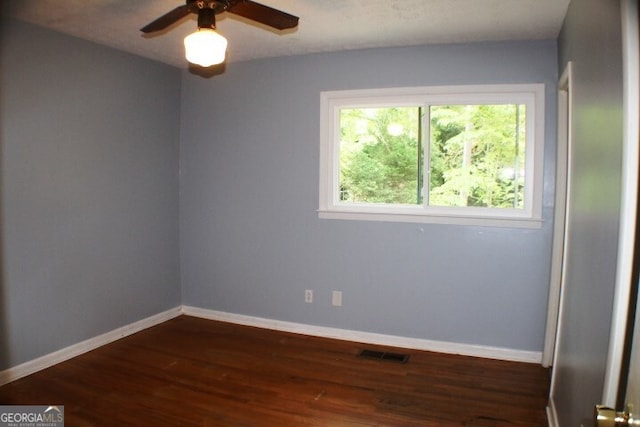 unfurnished room with a healthy amount of sunlight, dark wood-type flooring, and ceiling fan