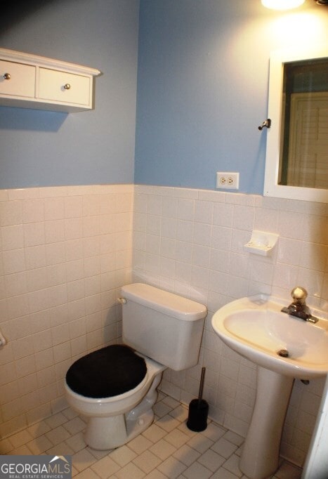 bathroom with tile walls, toilet, tile floors, and tasteful backsplash