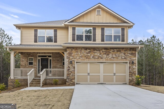 view of front of home with covered porch, a garage, and a front lawn