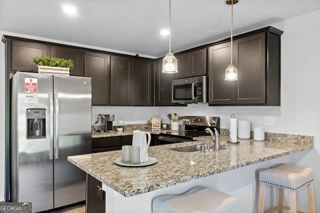 kitchen with dark brown cabinets, stainless steel appliances, hanging light fixtures, and a breakfast bar area