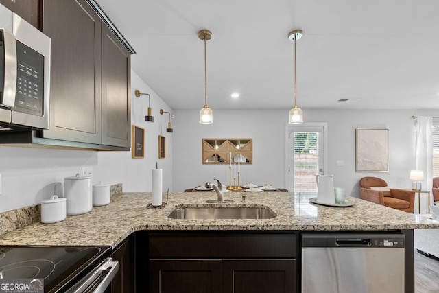 kitchen featuring pendant lighting, sink, appliances with stainless steel finishes, dark brown cabinets, and light stone counters