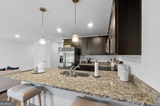 kitchen with dark brown cabinetry, sink, hanging light fixtures, stainless steel appliances, and dark hardwood / wood-style flooring