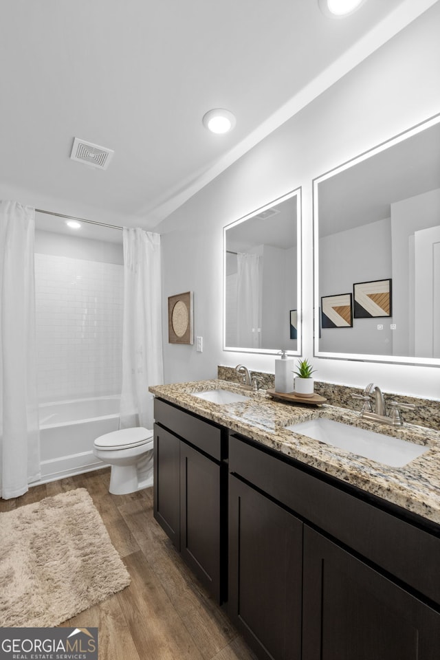 full bathroom with hardwood / wood-style floors, vanity, shower / tub combo, and toilet