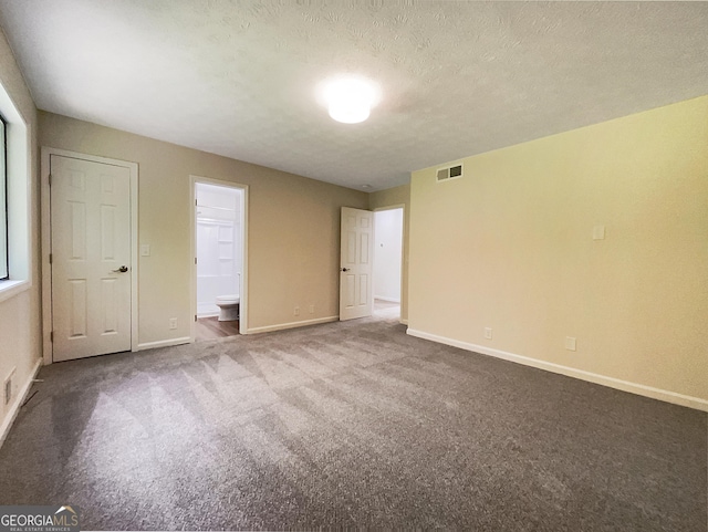 unfurnished bedroom featuring a textured ceiling, carpet floors, and ensuite bath