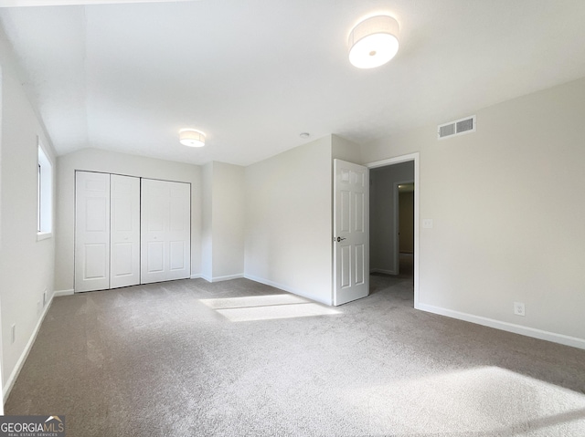 unfurnished bedroom featuring carpet flooring, a closet, and lofted ceiling