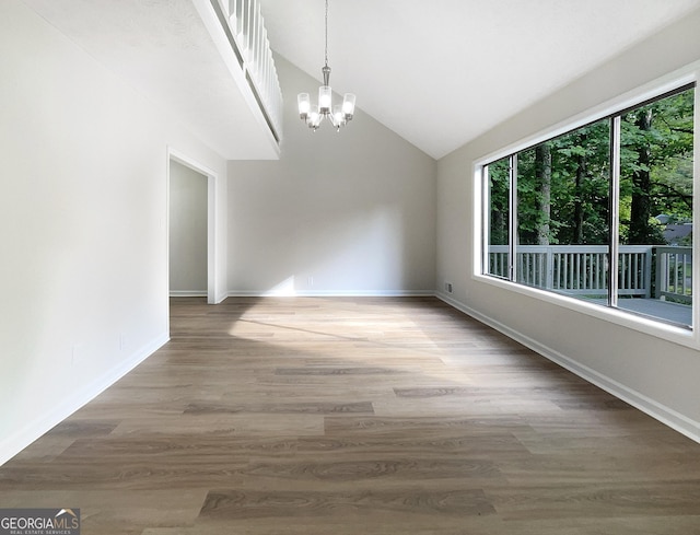 unfurnished dining area with hardwood / wood-style floors, lofted ceiling, and an inviting chandelier