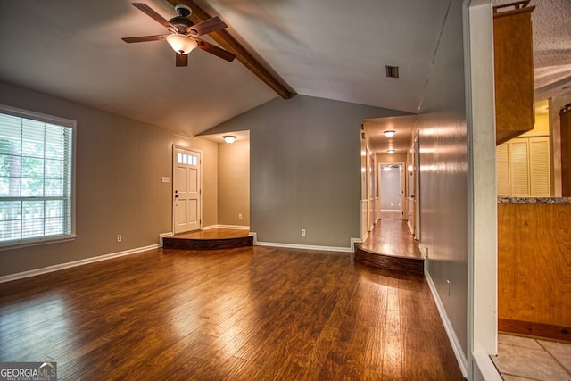 unfurnished living room with ceiling fan, lofted ceiling with beams, and dark hardwood / wood-style flooring