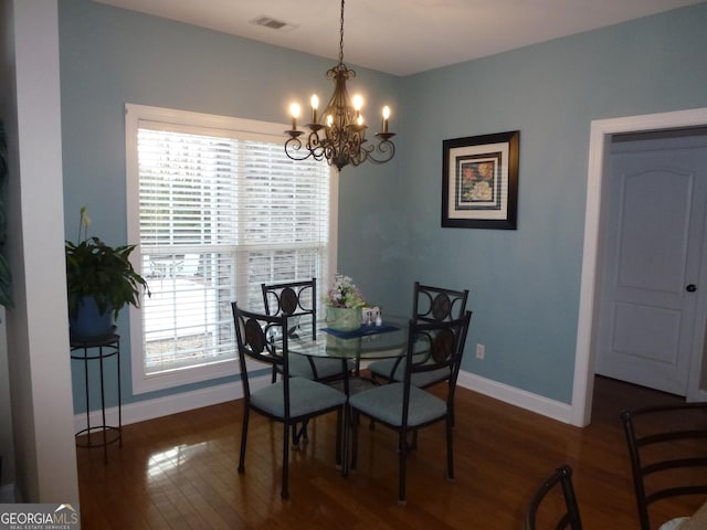 dining area featuring a wealth of natural light, a notable chandelier, and dark wood-type flooring