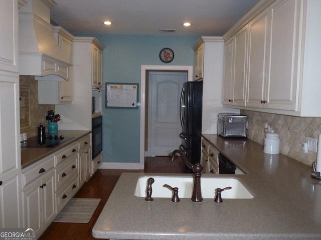 kitchen with black appliances, sink, tasteful backsplash, and premium range hood