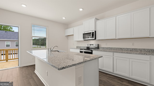 kitchen with dark wood-type flooring, appliances with stainless steel finishes, white cabinetry, and a kitchen island with sink