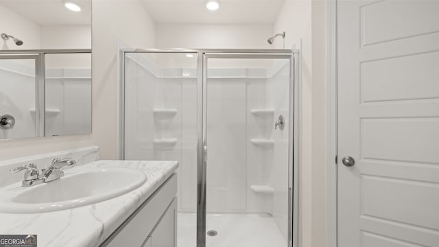 bathroom featuring a shower with shower door and vanity