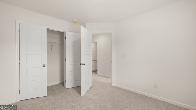 unfurnished bedroom with light colored carpet and a closet