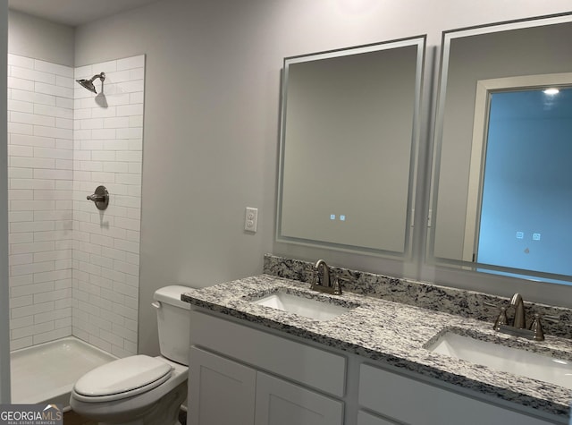 bathroom featuring a tile shower, vanity, and toilet