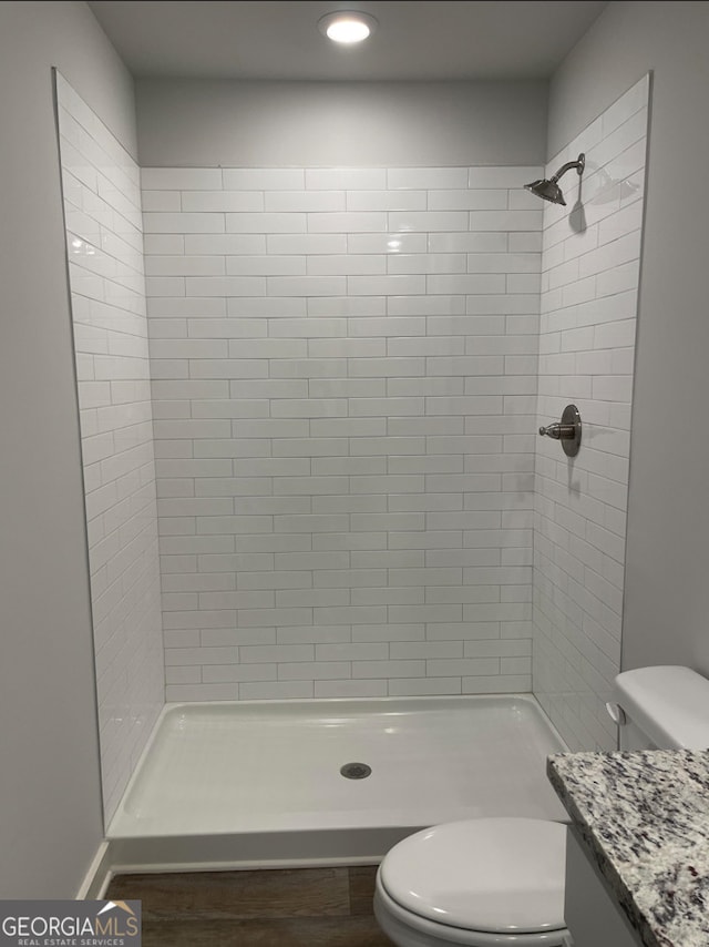 bathroom with a tile shower, vanity, and toilet