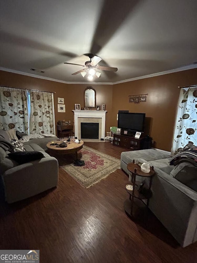 living room featuring a fireplace with flush hearth, a ceiling fan, ornamental molding, and wood finished floors