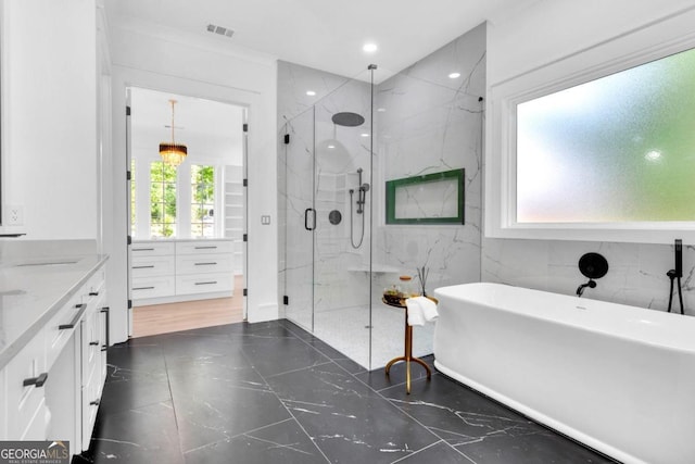 bathroom featuring plus walk in shower, vanity, and tile walls