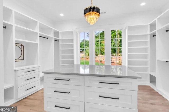 spacious closet with an inviting chandelier and light wood-type flooring