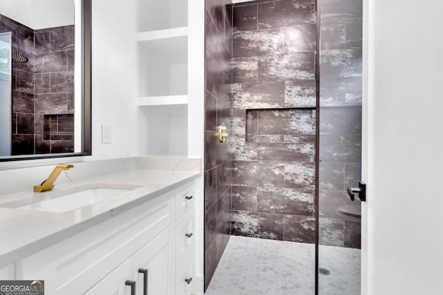 bathroom featuring a tile shower and vanity