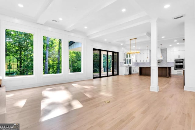 unfurnished living room with beamed ceiling, a notable chandelier, and light wood-type flooring