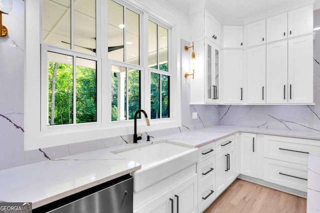 kitchen featuring white cabinets, decorative backsplash, light stone countertops, and sink