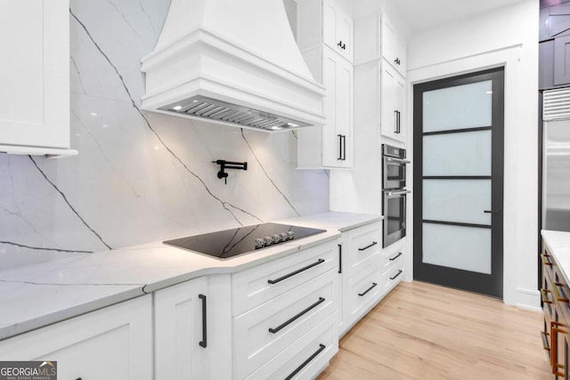 kitchen featuring white cabinets, tasteful backsplash, light hardwood / wood-style floors, custom range hood, and stainless steel appliances