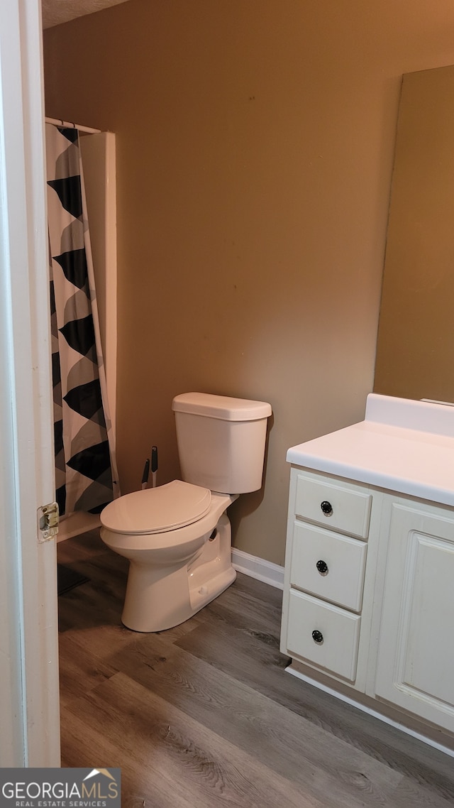 bathroom featuring wood-type flooring, vanity, and toilet