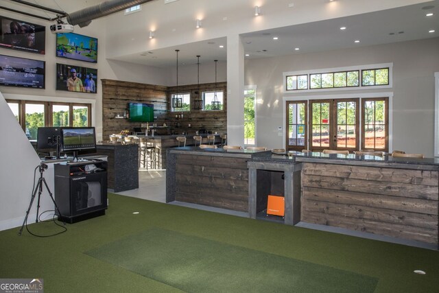 kitchen featuring a wealth of natural light, french doors, a towering ceiling, and golf simulator